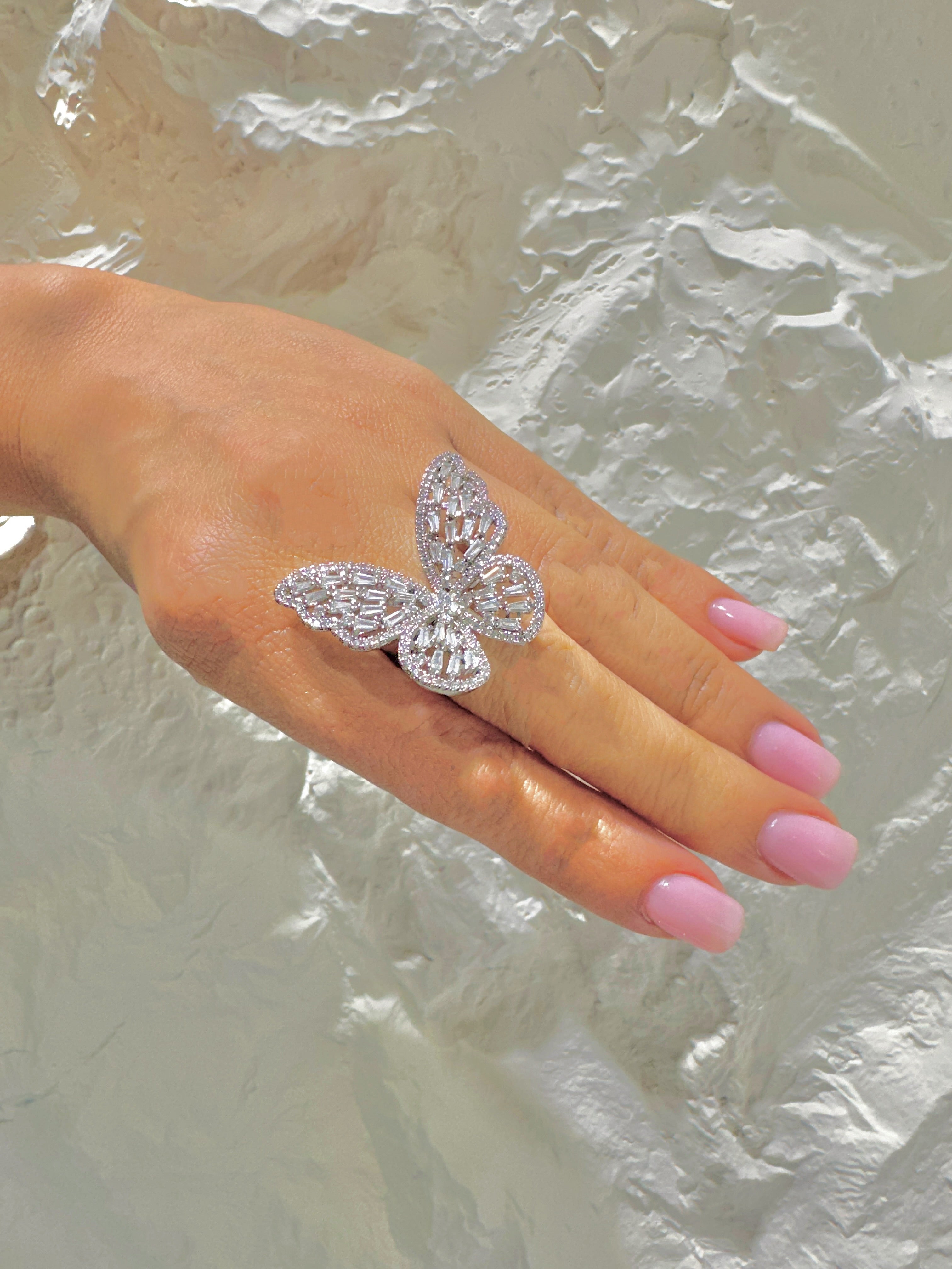 Silver butterfly ring on a hand with pink nail polish 